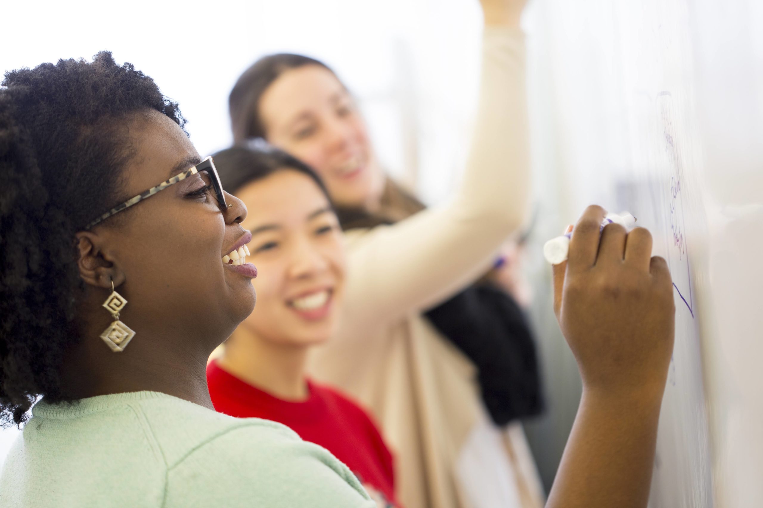 three women writing on whiteboard